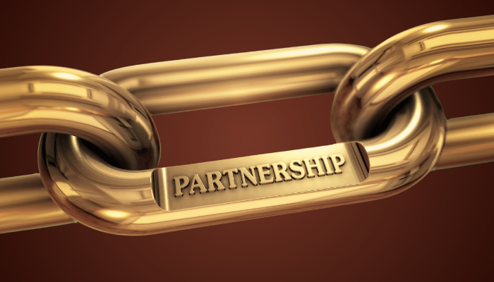 Catena dorata con la parola "Partnership" incisa su un anello, simbolo di unione e collaborazione duratura.